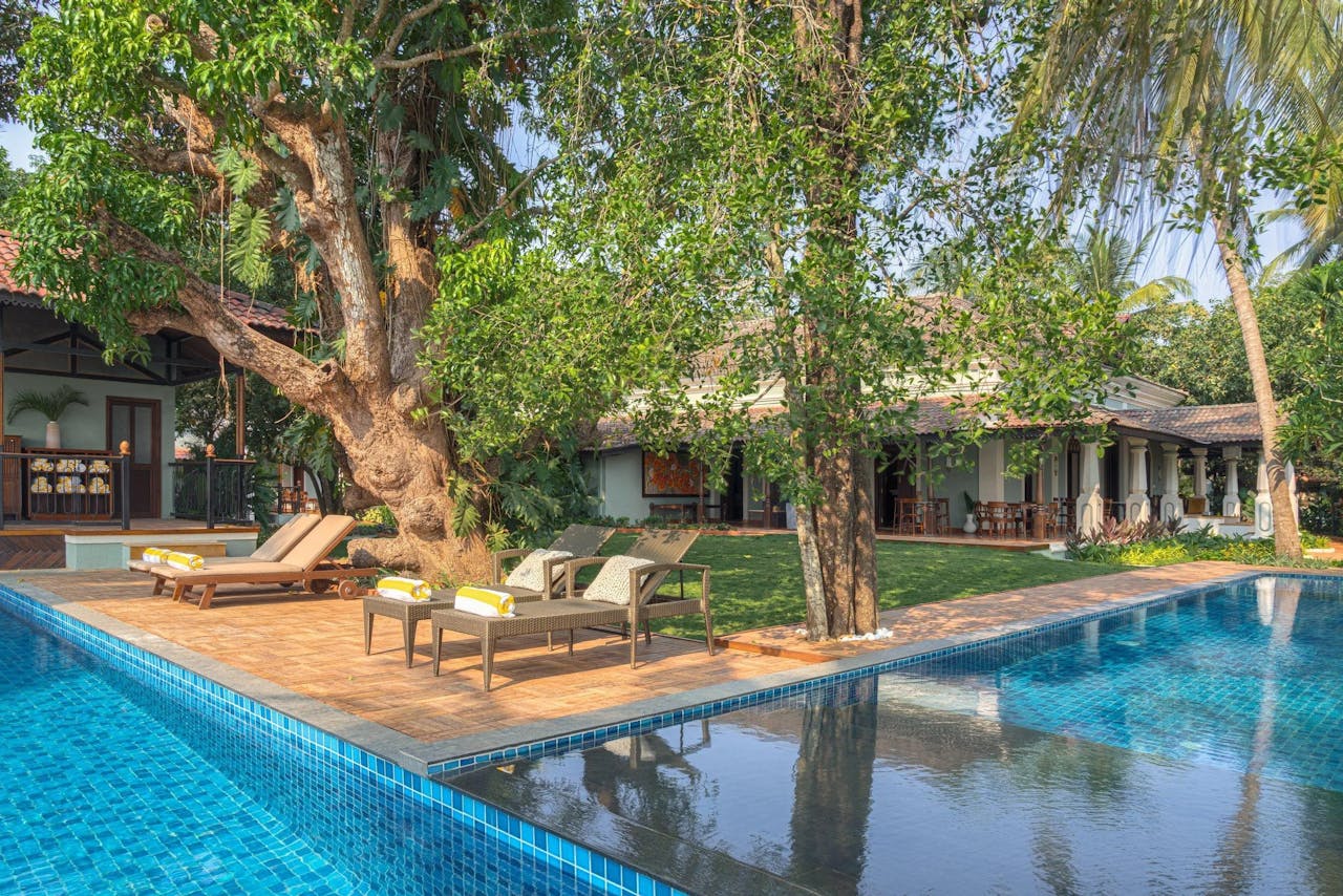 Elegant villa with pool surrounded by lush greenery in Arpora, Goa, India.
